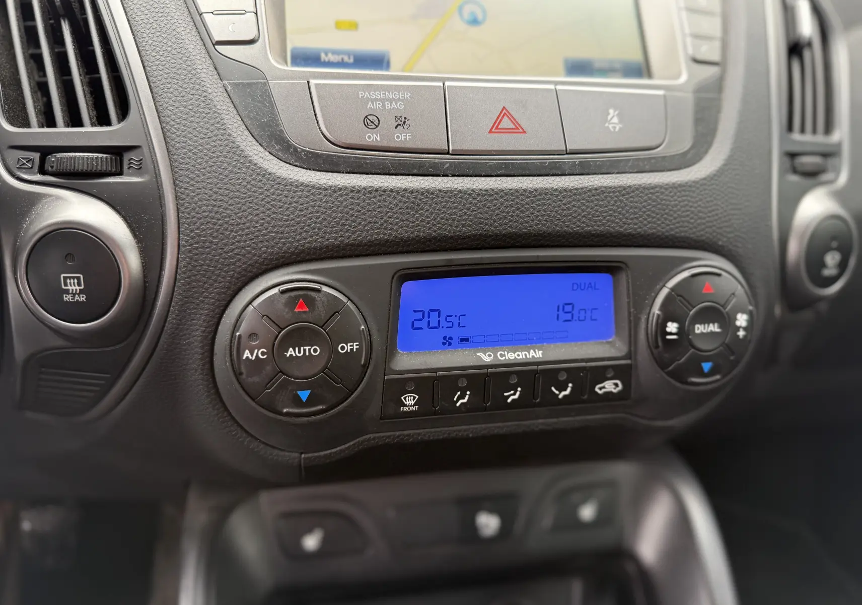 Détail de la console centrale du Hyundai ix35 2014 montrant la climatisation automatique bi-zone avec écran bleu et commandes circulaires.