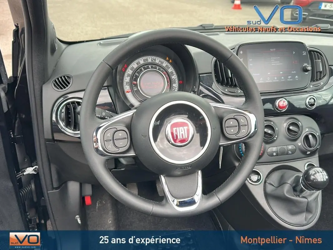Vue intérieure centrée sur le volant et le tableau de bord noir de la FIAT 500C 2024 avec boîte manuelle.
