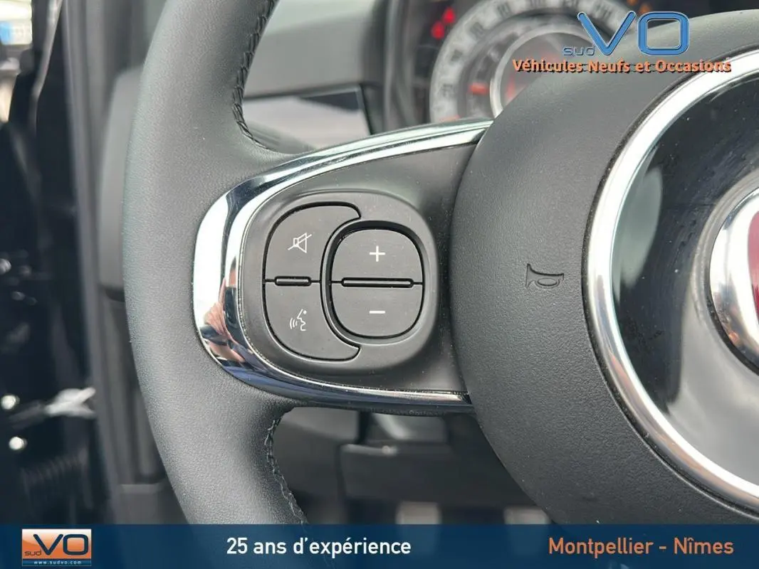 Gros plan sur les commandes au volant côté gauche du Fiat 500C noir 2024 avec volant en cuir et détails chromés.