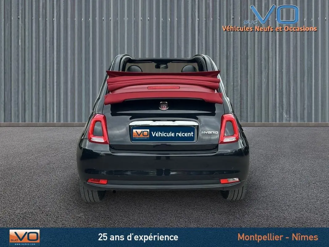 Vue arrière d'une FIAT 500C noire 2024 avec toit rouge décapoté, mettant en valeur la version hybride et la roue de secours.