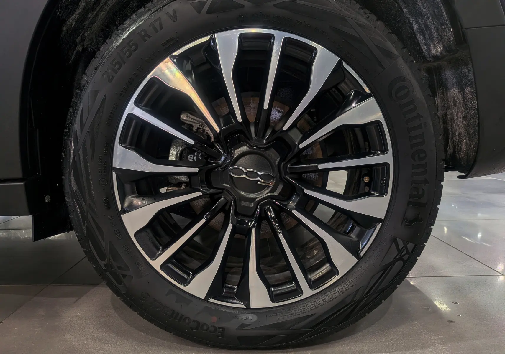 Gros plan sur la jante alliage bicolore noire et argentée du FIAT 500X Bleu Venezia, roue avant droite visible.