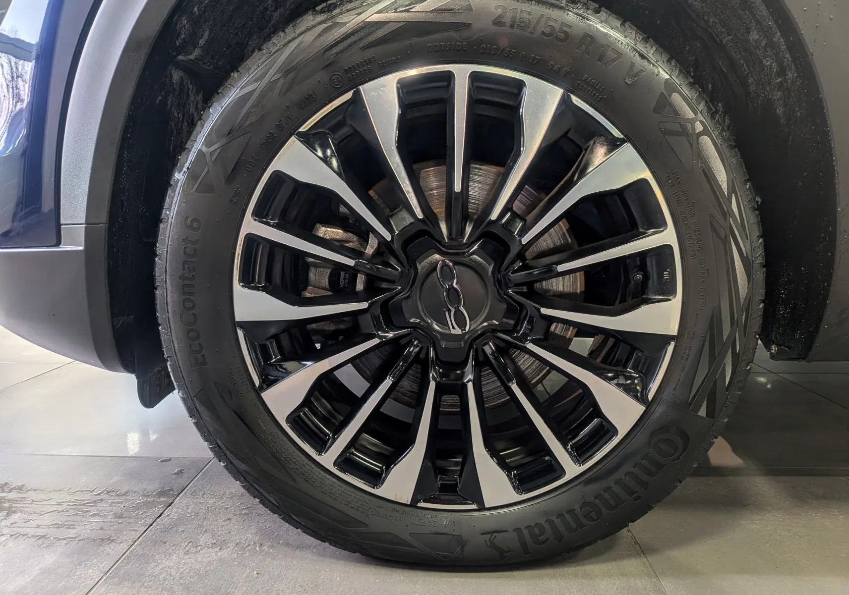 Gros plan sur la jante alliage bicolore noire et argentée du FIAT 500X Bleu Venezia, pneu Continental visible.