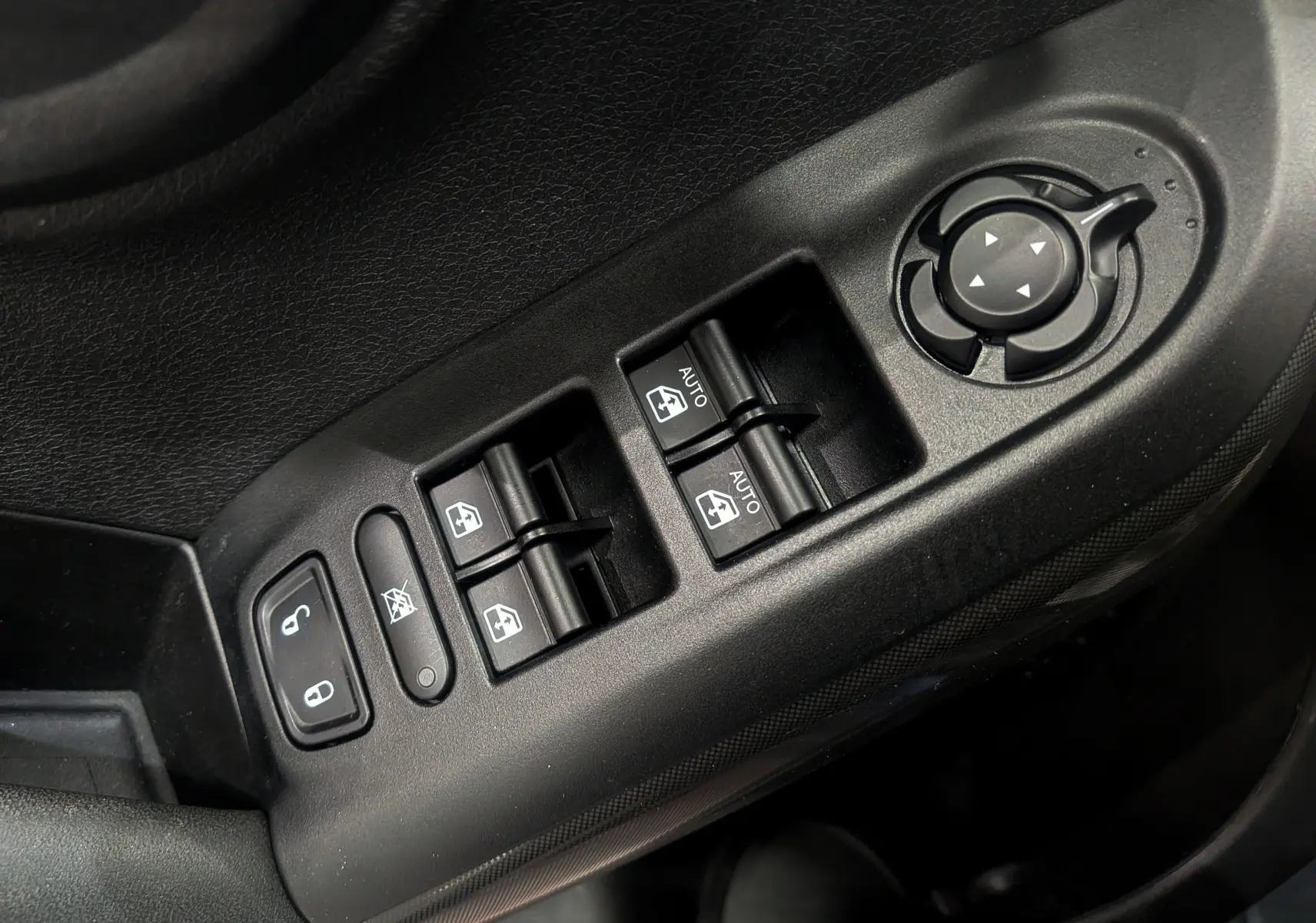 Gros plan sur les commandes électriques des vitres et rétroviseurs côté conducteur d'une Fiat 500X 2024, finition noire.