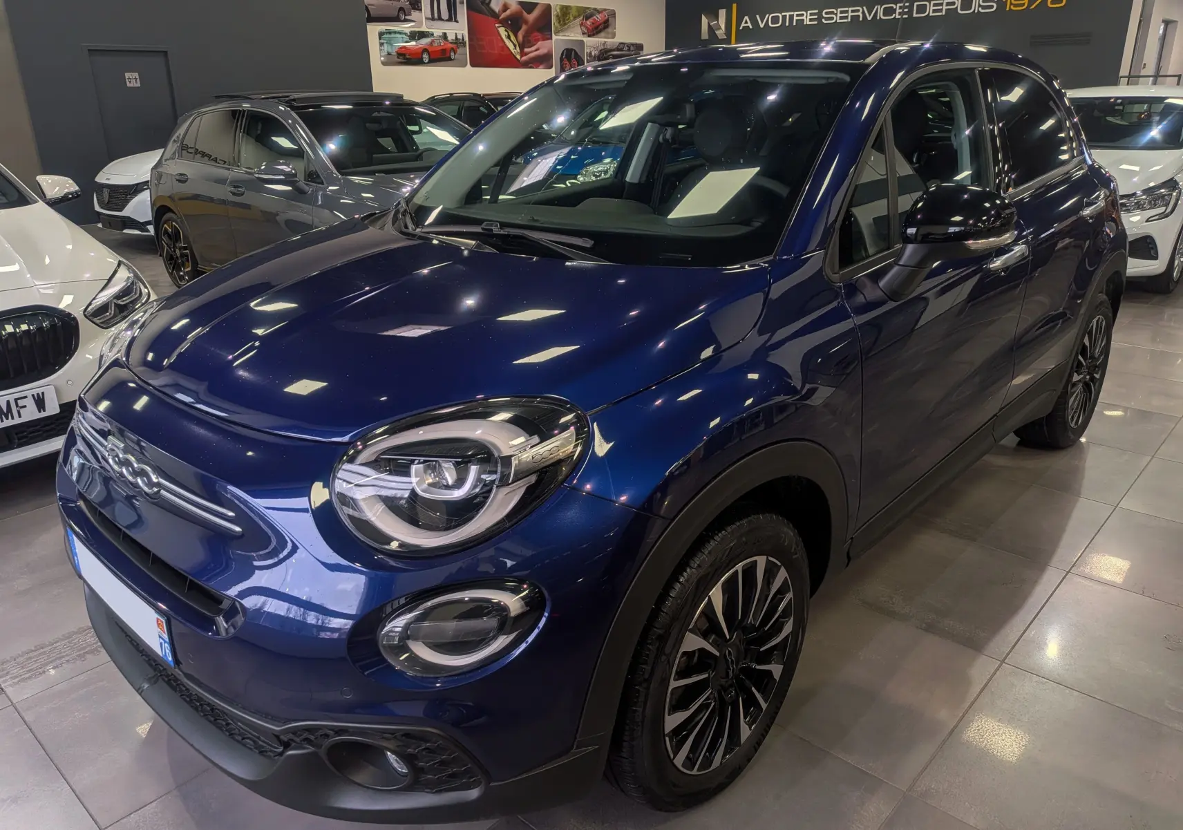 Vue 3/4 avant droite d'une FIAT 500X bleu Venezia 2024 avec jantes noires et toit noir en concession.