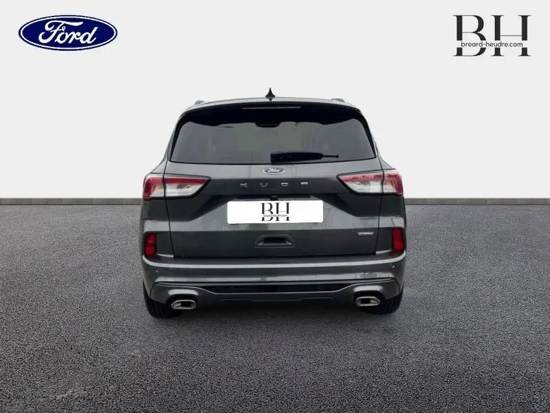 Vue arrière d'un Ford Kuga 2023 gris Magnetic Métallisé avec double sortie d'échappement et vitres arrière surteintées.