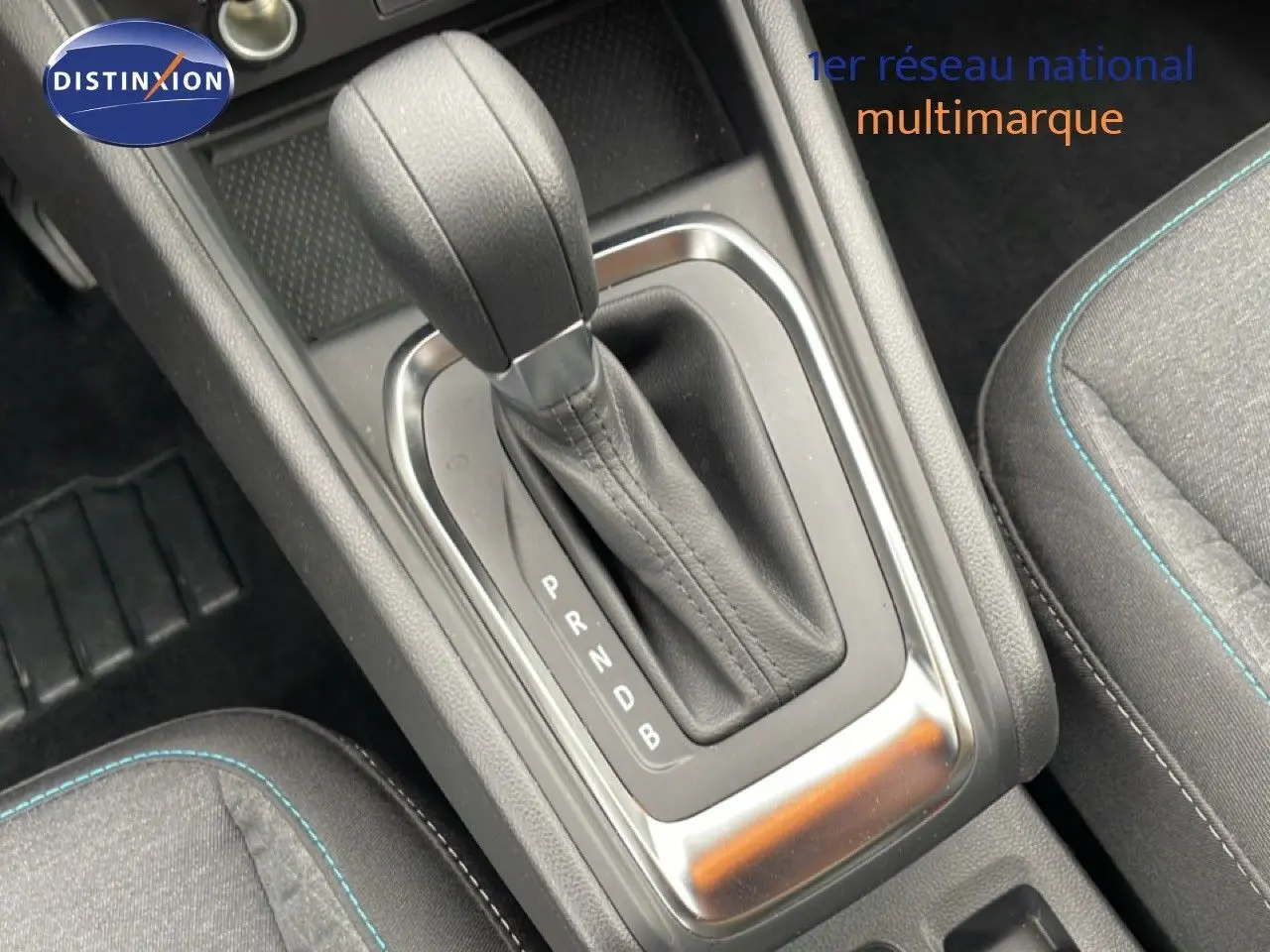 Le levier de vitesses automatique noir de la Renault Symbioz E-Tech, entouré de sièges en tissu gris avec surpiqûres bleues.