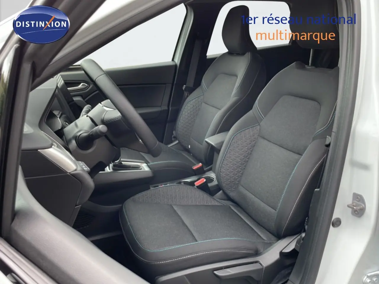 Vue intérieure côté gauche de la Renault Symbioz blanc nacré, sièges tissu noir avec surpiqûres bleues et volant multifonction.