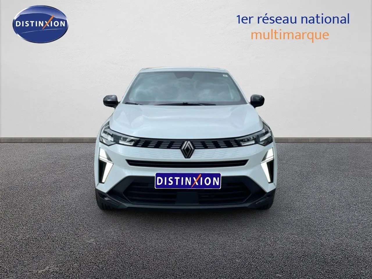 Vue avant d'une Renault Symbioz blanc nacré avec calandre noire et feux LED verticaux allumés sur un sol gris.
