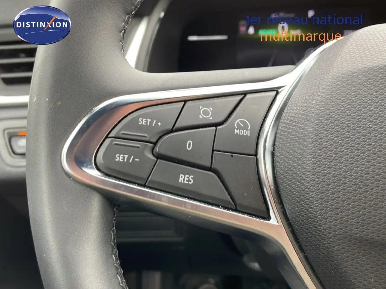 Gros plan sur les commandes au volant à gauche du Renault Symbioz blanc nacré, boutons de régulateur de vitesse visibles.