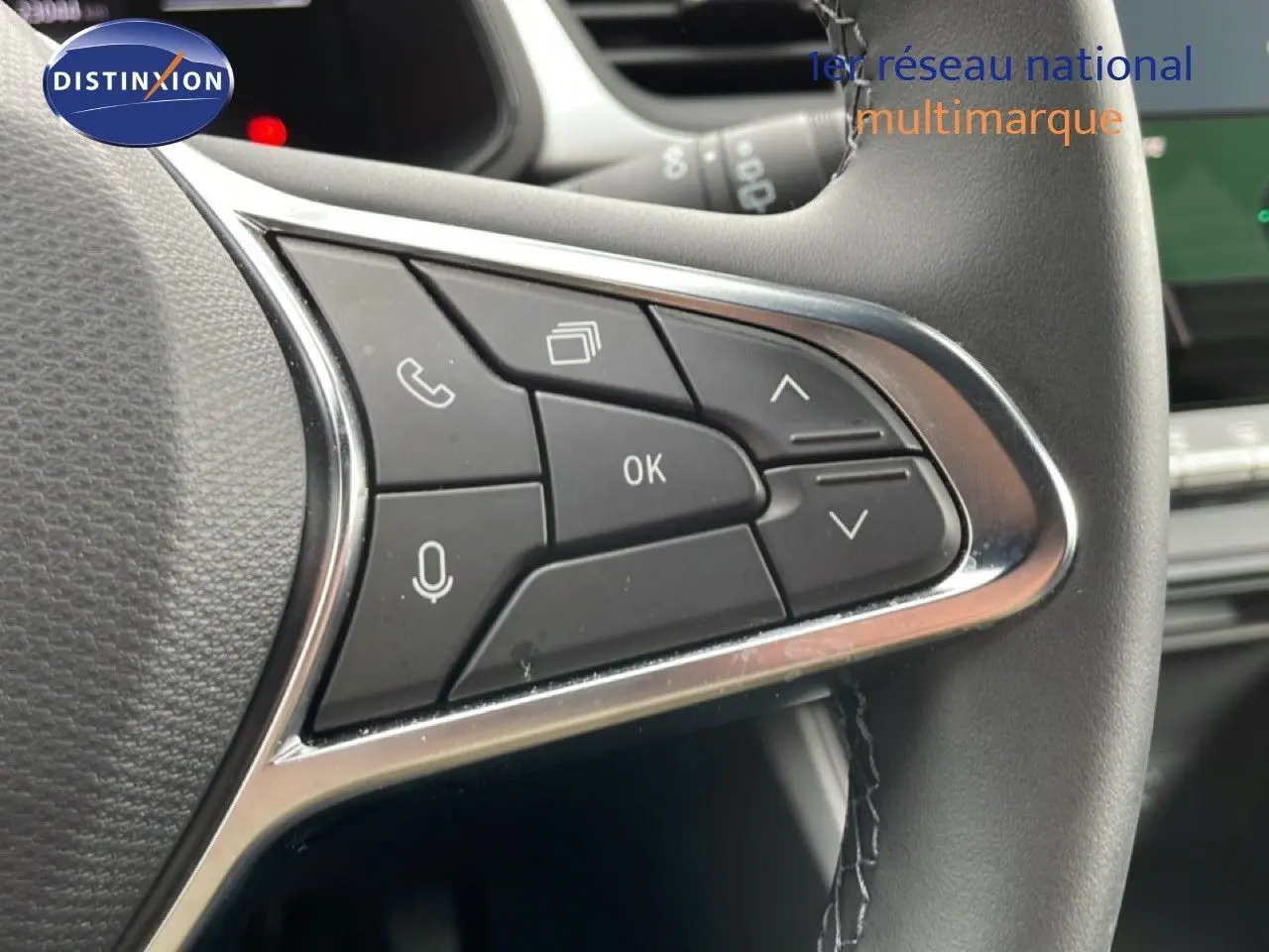 Gros plan sur les commandes au volant côté gauche du Renault Symbioz blanc nacré, avec boutons multifonctions et finition chromée.