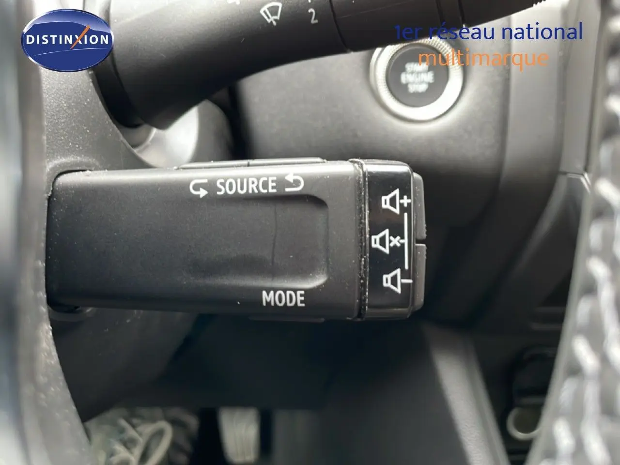 Gros plan sur la commande multifonction noire côté gauche du volant du Renault Symbioz blanc nacré, avec bouton start visible.