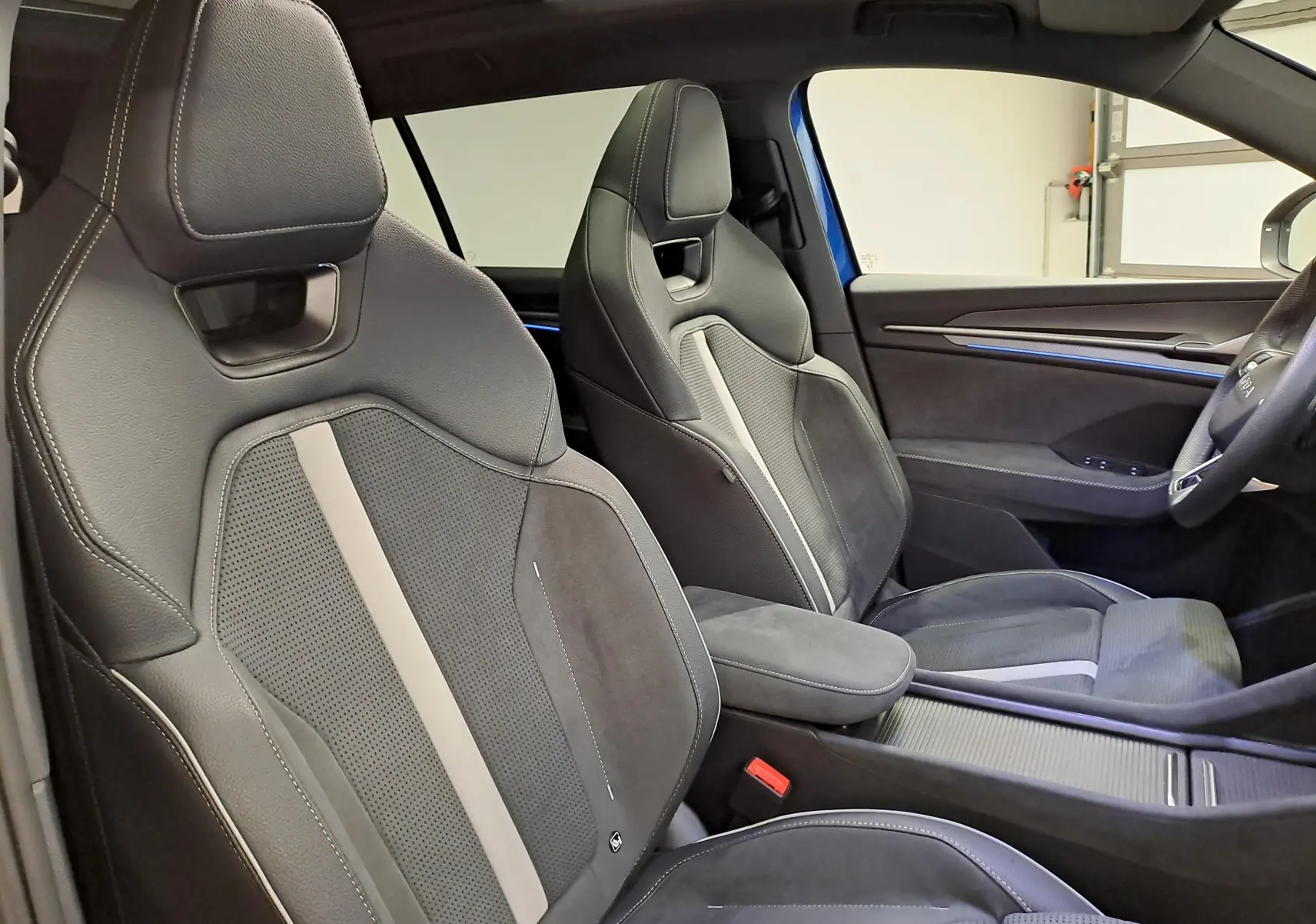 Vue intérieure côté droit du Skoda Kodiaq Sportline 2025, sièges sport en cuir noir avec surpiqûres blanches et insert gris.