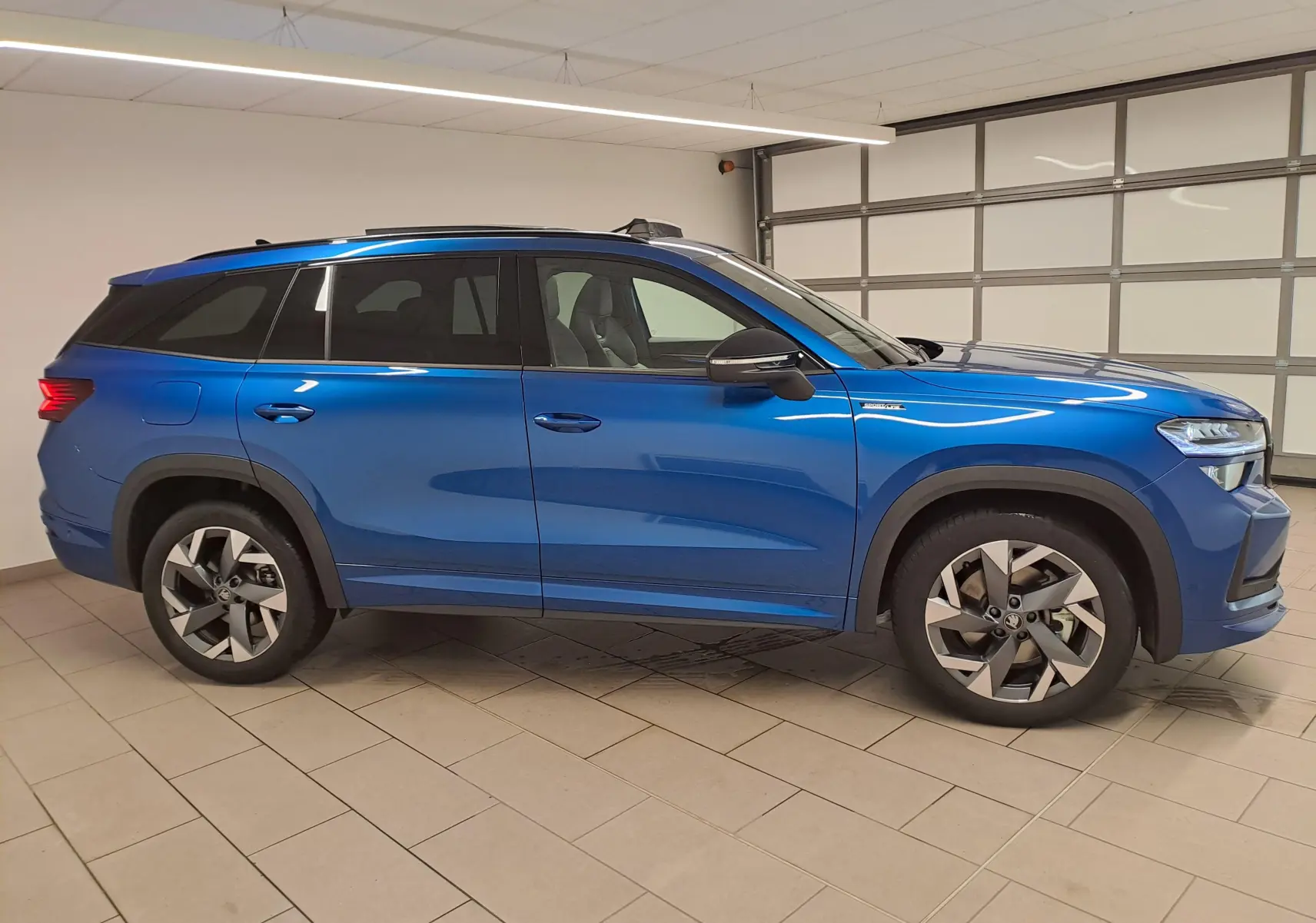 Vue de profil côté gauche d'un Skoda Kodiaq 2025 Bleu RS avec toit panoramique et jantes alliage sport.