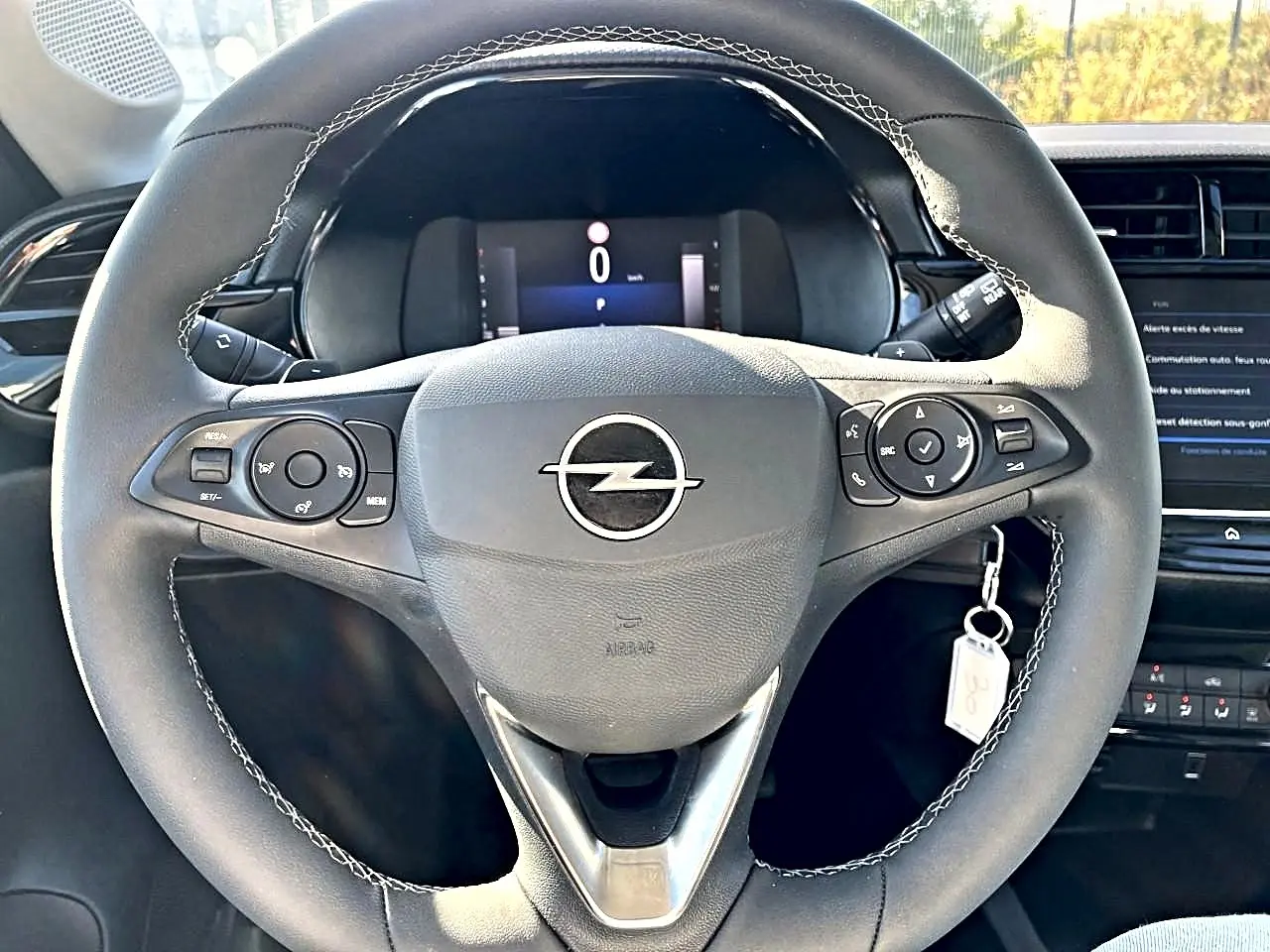 Vue frontale du volant sport noir avec surpiqûres blanches de l'Opel Corsa 1.2 turbo 100 edition 2025, tableau de bord en arrière-plan.