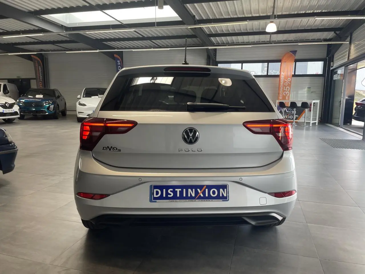 Vue arrière d'une Volkswagen Polo gris clair 2024 avec feux LED et lunette arrière surteintée en showroom.