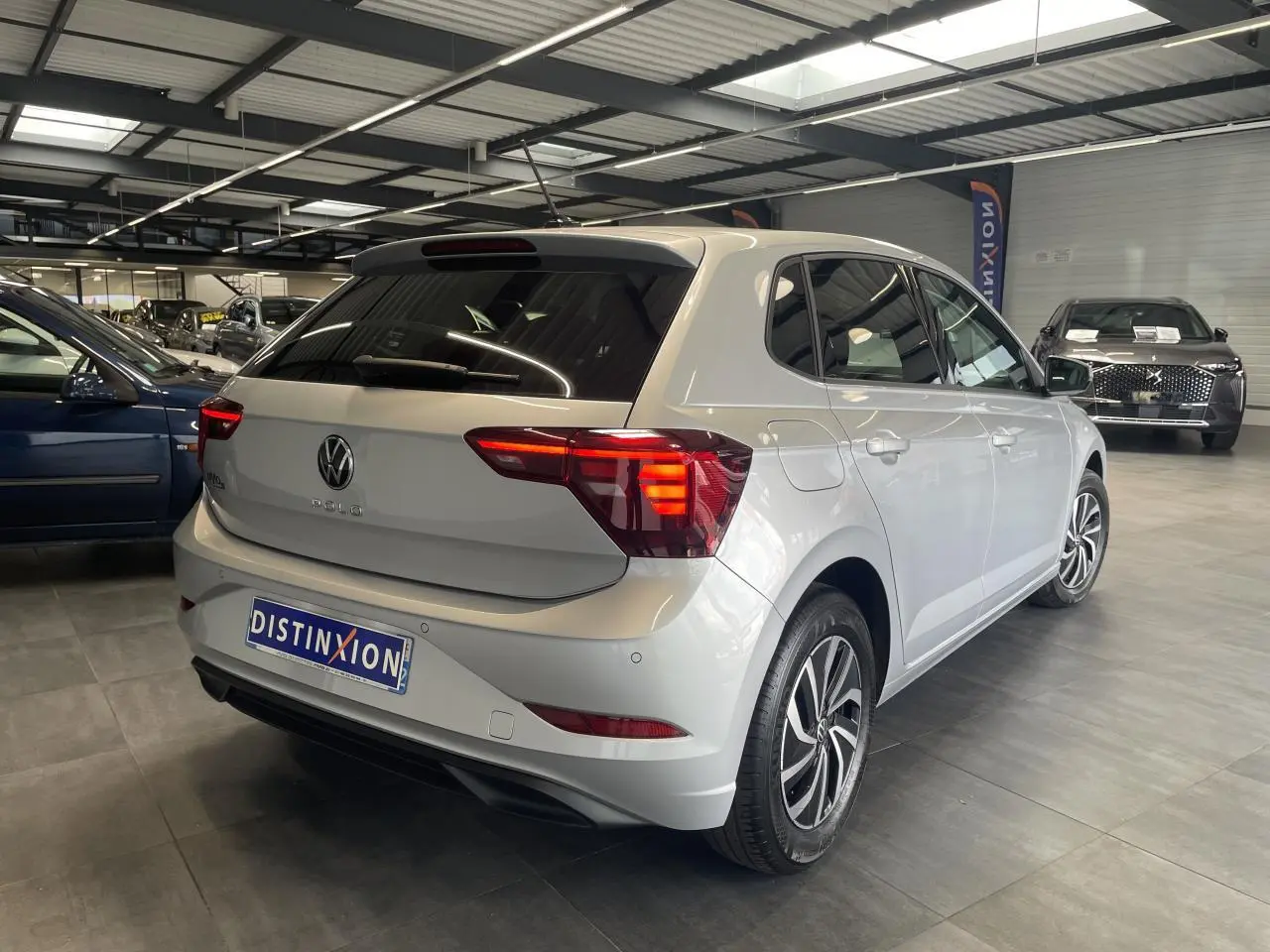 Volkswagen Polo gris clair vue 3/4 arrière droit en intérieur avec vitres arrière surteintées.