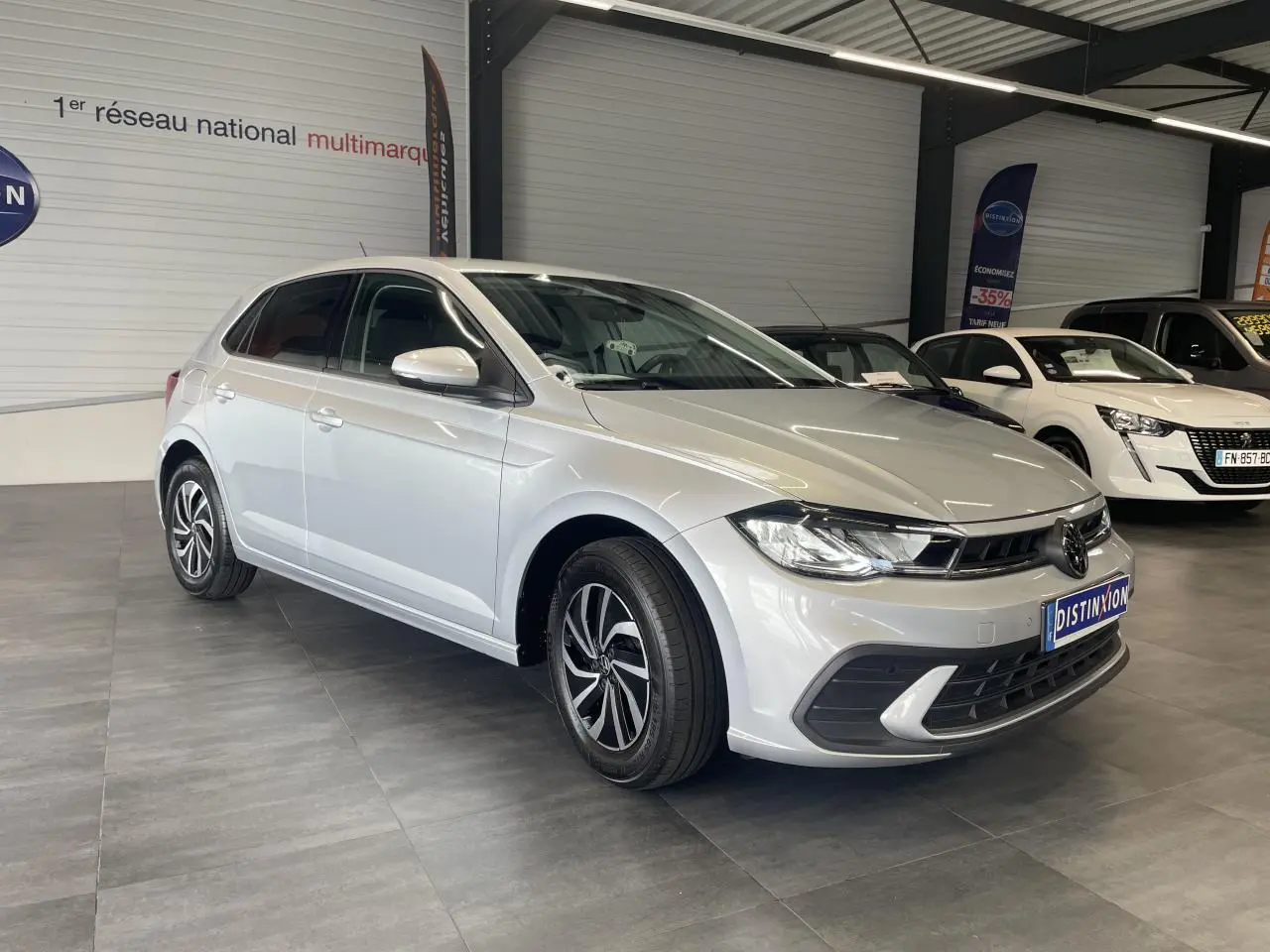 Volkswagen Polo gris clair vue 3/4 avant droit en intérieur avec jantes alliage et calandre chromée.