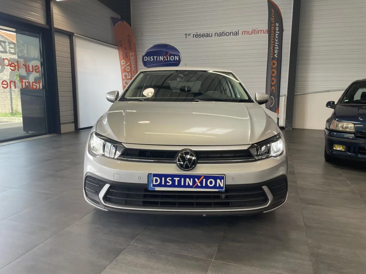Vue frontale d'une Volkswagen Polo gris clair 2024 avec calandre noire et logo VW bien visible en intérieur showroom.