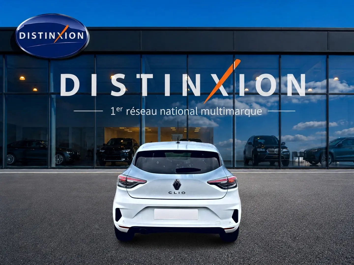 Vue arrière d'une Renault Clio V blanche 2025 stationnée devant une vitrine avec logo Distinxion.
