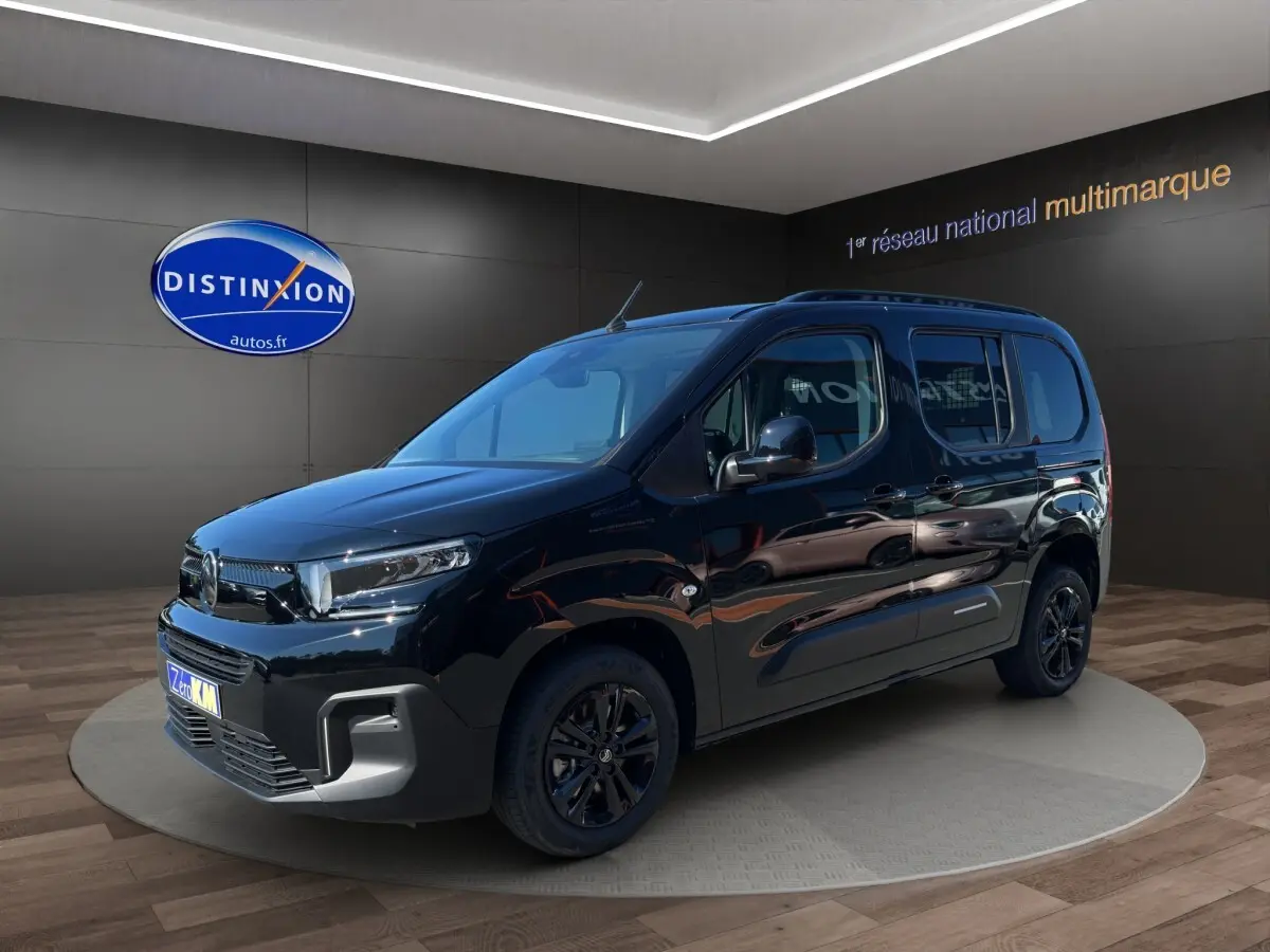 Citroën Berlingo noir en 3/4 avant droit, avec jantes noires et vitres latérales teintées, en intérieur showroom.