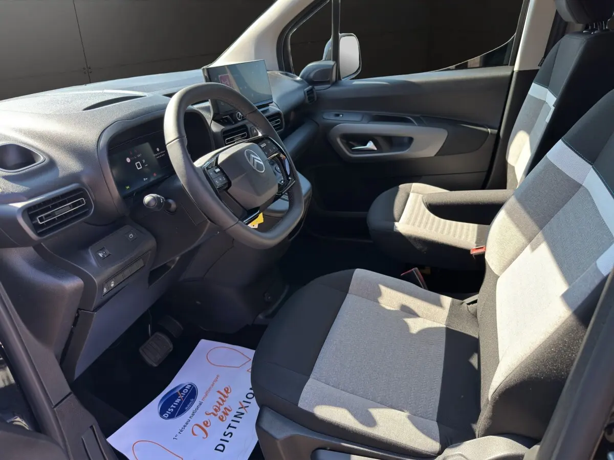 Intérieur avant droit du Citroën Berlingo noir 2026, avec tableau de bord moderne et sièges bicolores gris et noir.
