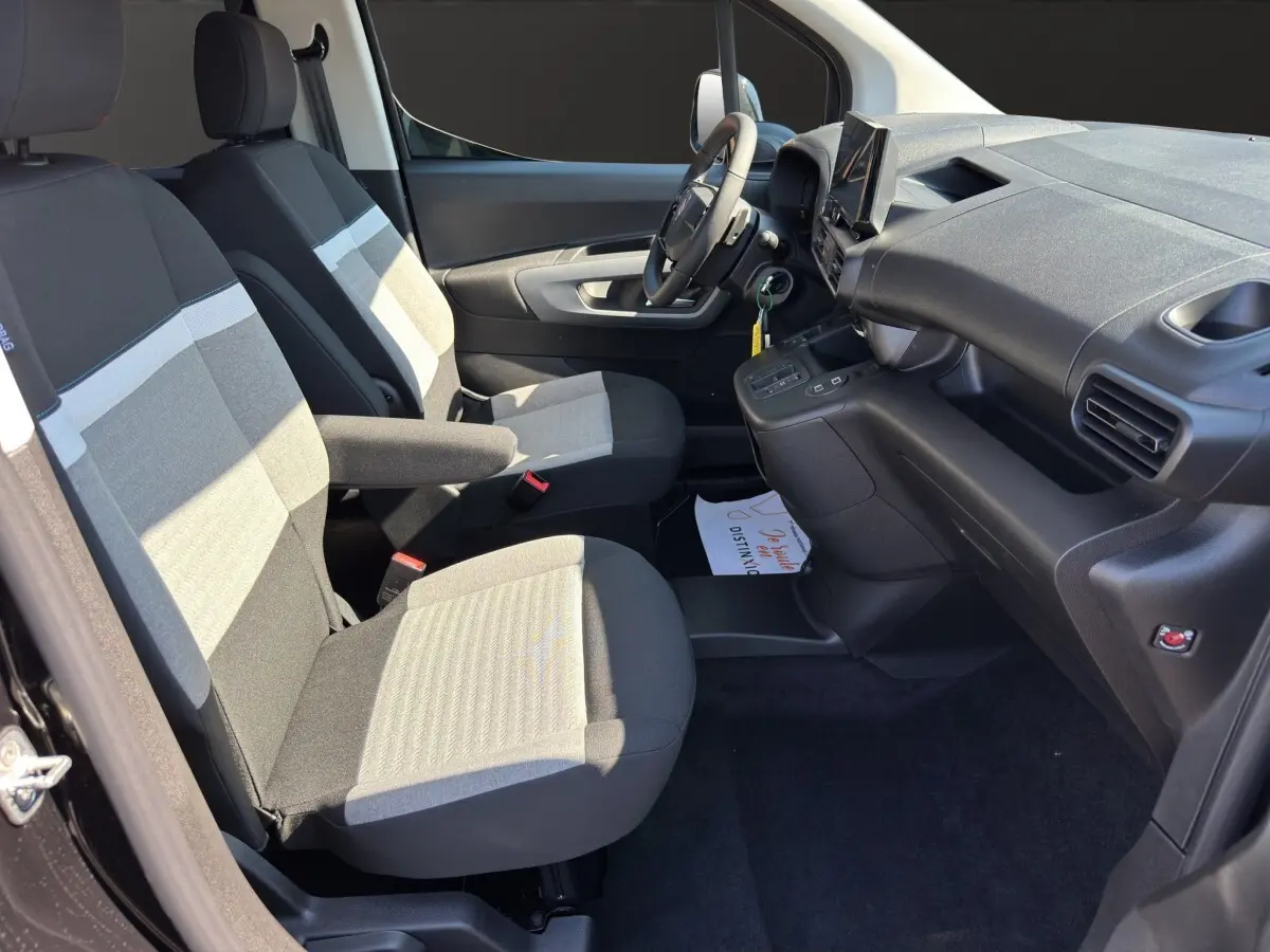 Vue intérieure côté conducteur du Citroën Berlingo 2026, sièges tissu gris et tableau de bord noir avec écran tactile.