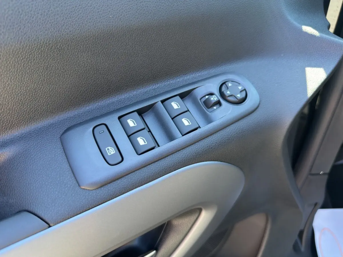 Vue rapprochée des commandes des vitres et des rétroviseurs sur la porte côté conducteur du Citroën Berlingo noir 2026.