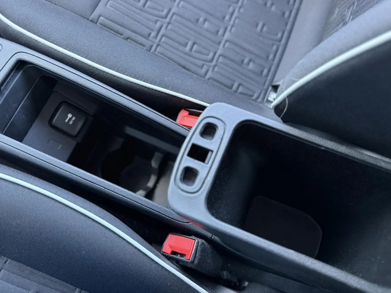 Gros plan sur la console centrale ouverte avec accoudoir et sellerie tissu noir du Fiat 500 électrique blanc Arctic.