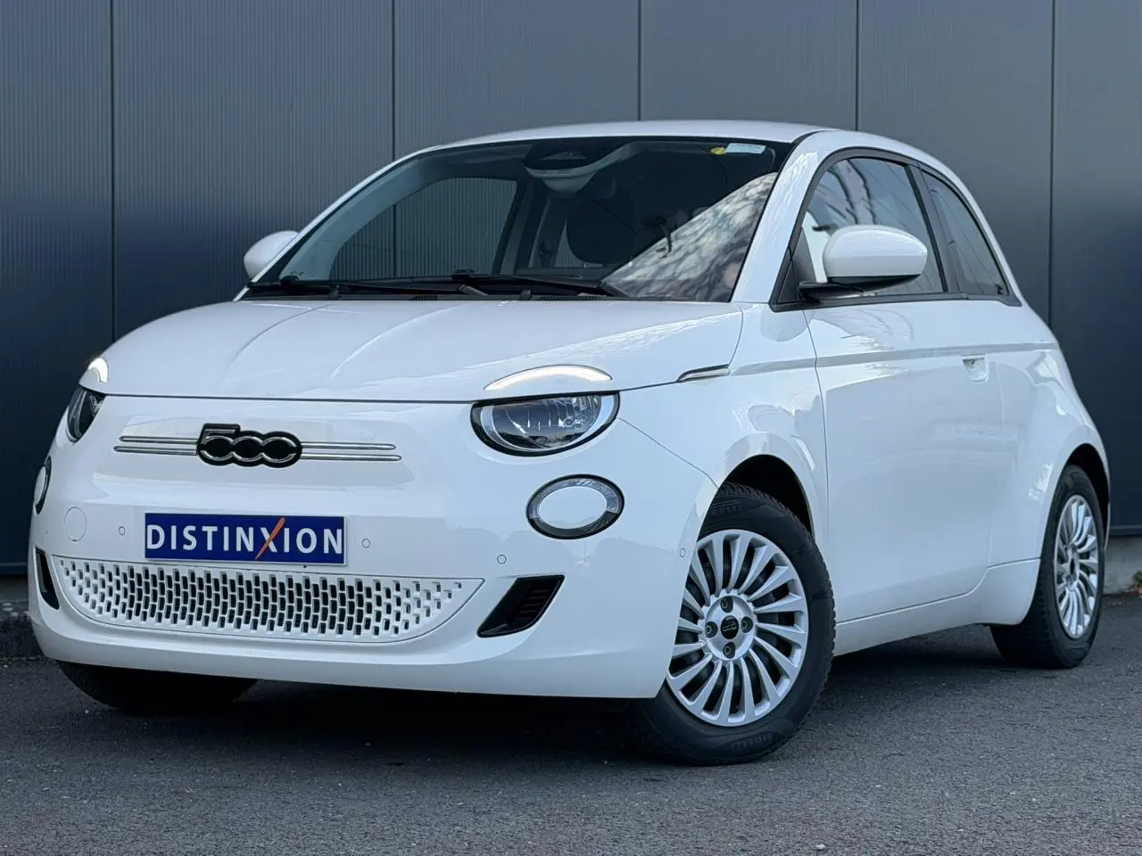 Vue 3/4 avant droite d'une Fiat 500 électrique blanche Arctic avec jantes multibranches et calandre épurée.