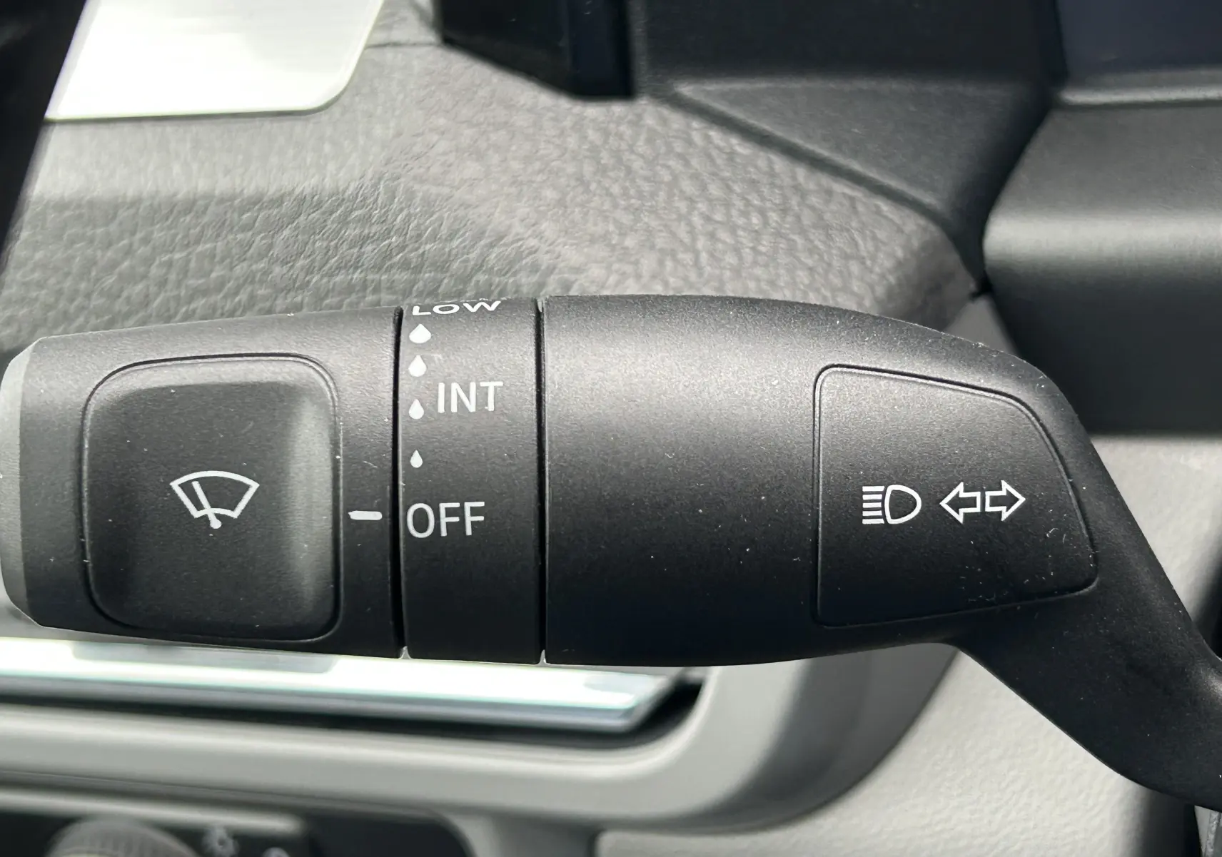 Gros plan sur la commande de l’essuie-glace et clignotant du Volkswagen Transporter T7 Business, intérieur gris.