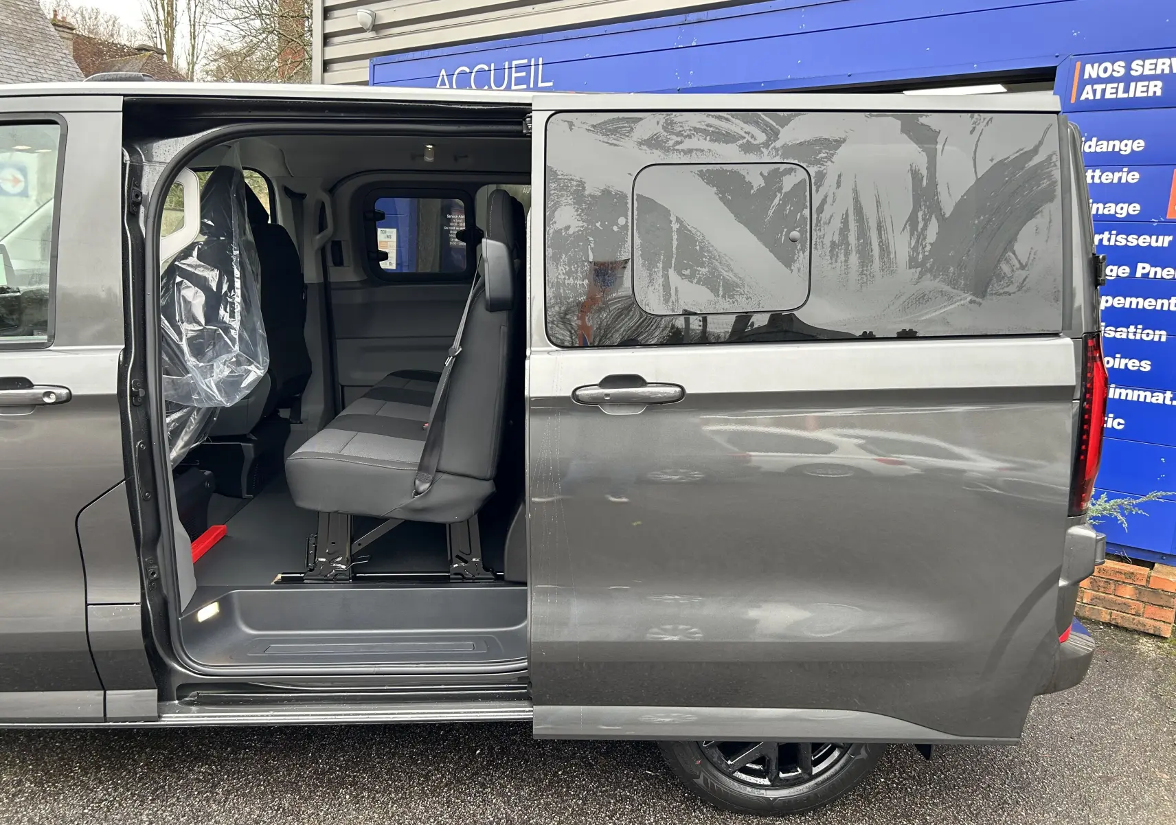 Vue latérale droite d’un Volkswagen Transporter T7 ProCab graphite Dust avec porte coulissante ouverte montrant les sièges cabine.