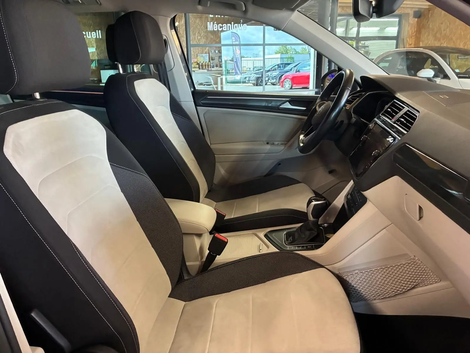 Vue intérieure côté droit du Volkswagen Tiguan 2023, sièges bicolores beige et noir avec tableau de bord moderne.