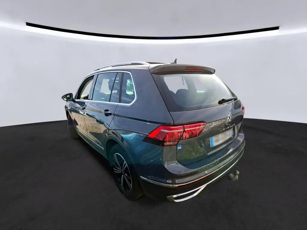 Volkswagen Tiguan gris 2023 vu en 3/4 arrière droit avec toit ouvrant et attelage visible.
