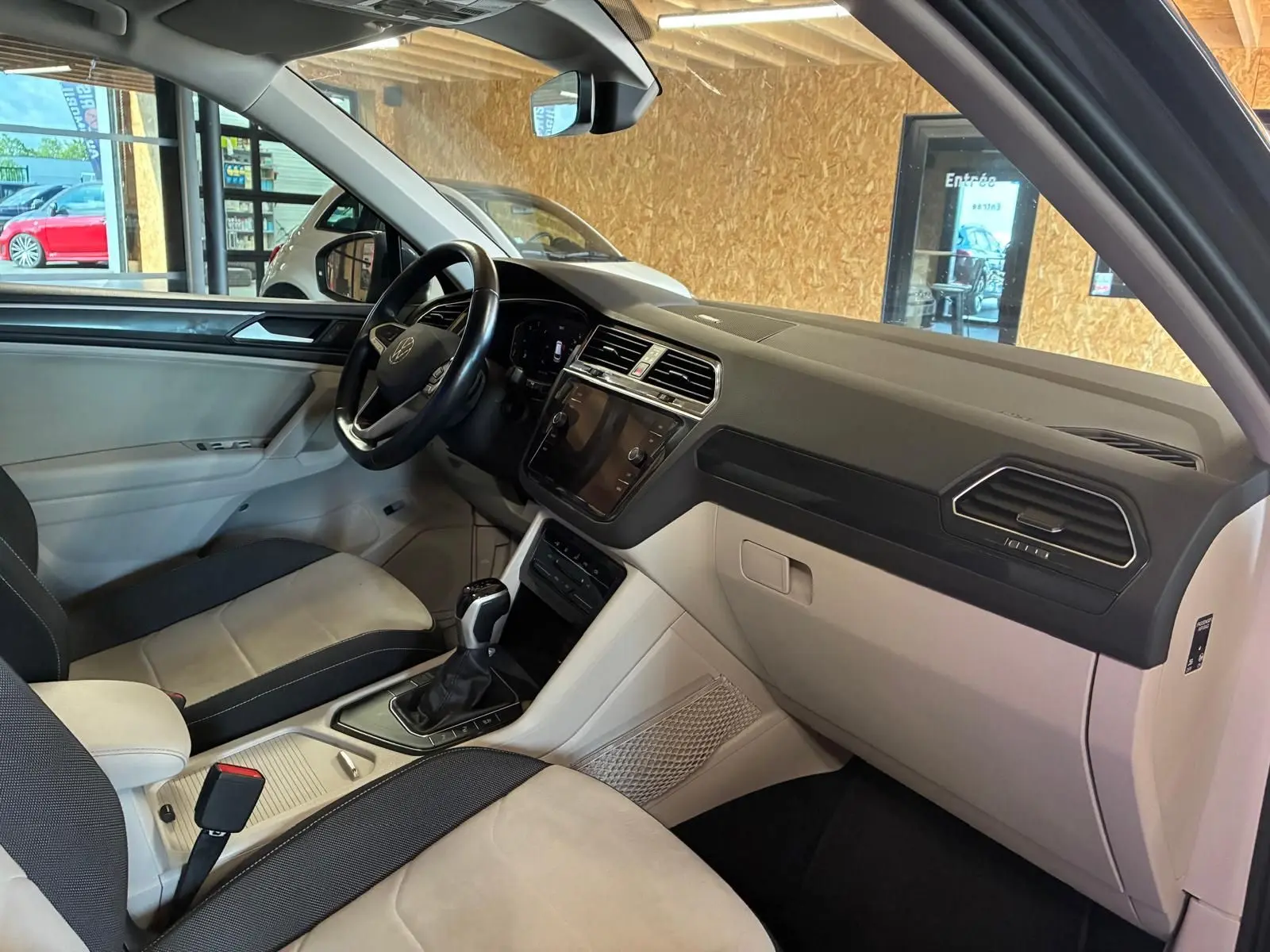 Vue intérieure côté passager avant du Volkswagen Tiguan 2.0 TDI gris, montrant tableau de bord et console centrale.