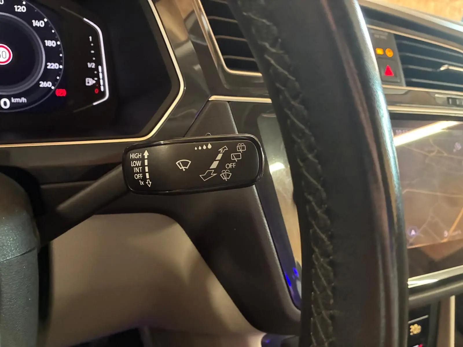 Gros plan sur la commande d’essuie-glace à gauche du volant dans l’habitacle du Volkswagen Tiguan gris 2023.