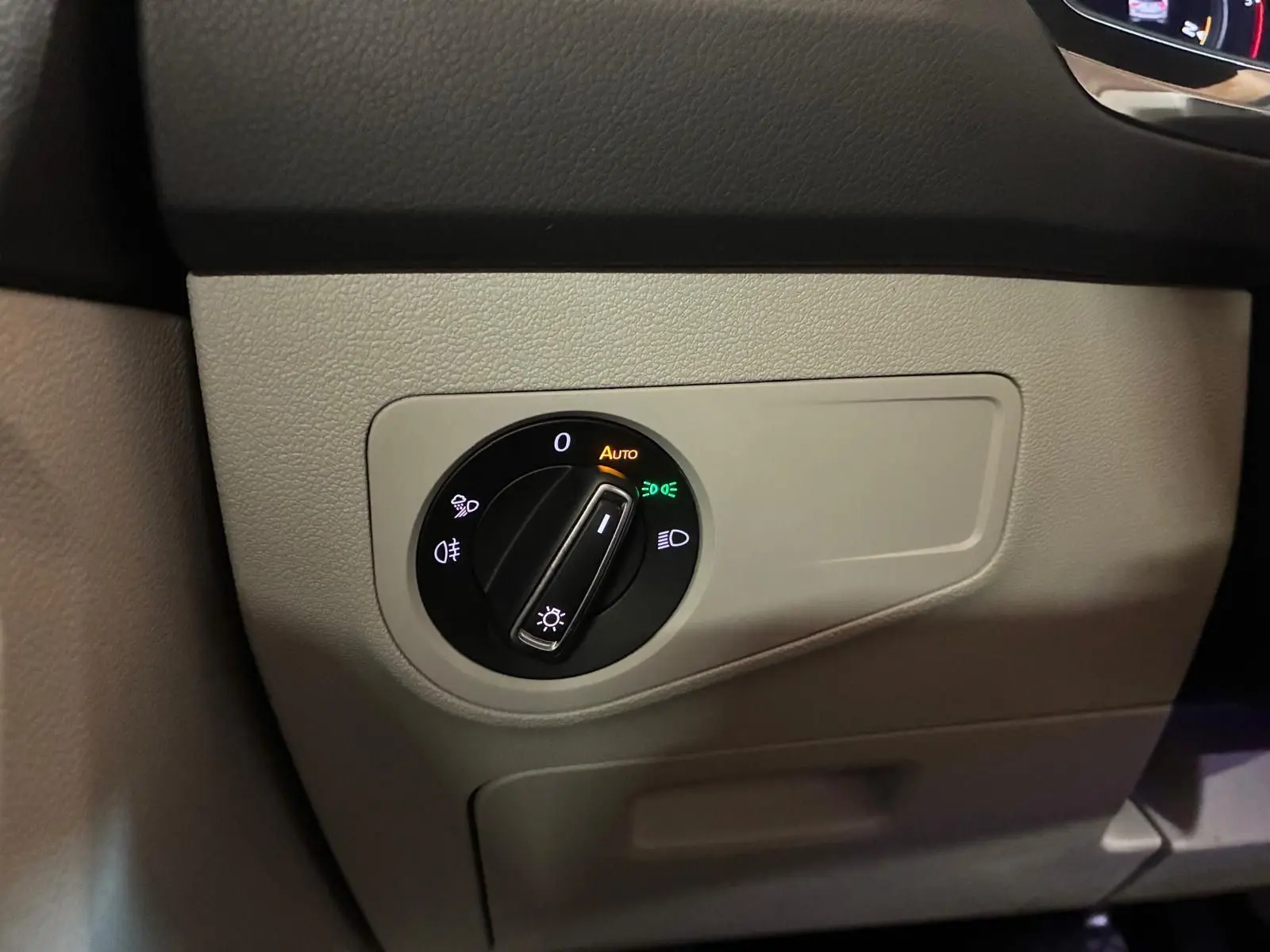 Gros plan sur le bouton de commande des phares dans l'habitacle beige du Volkswagen Tiguan 2023 gris.