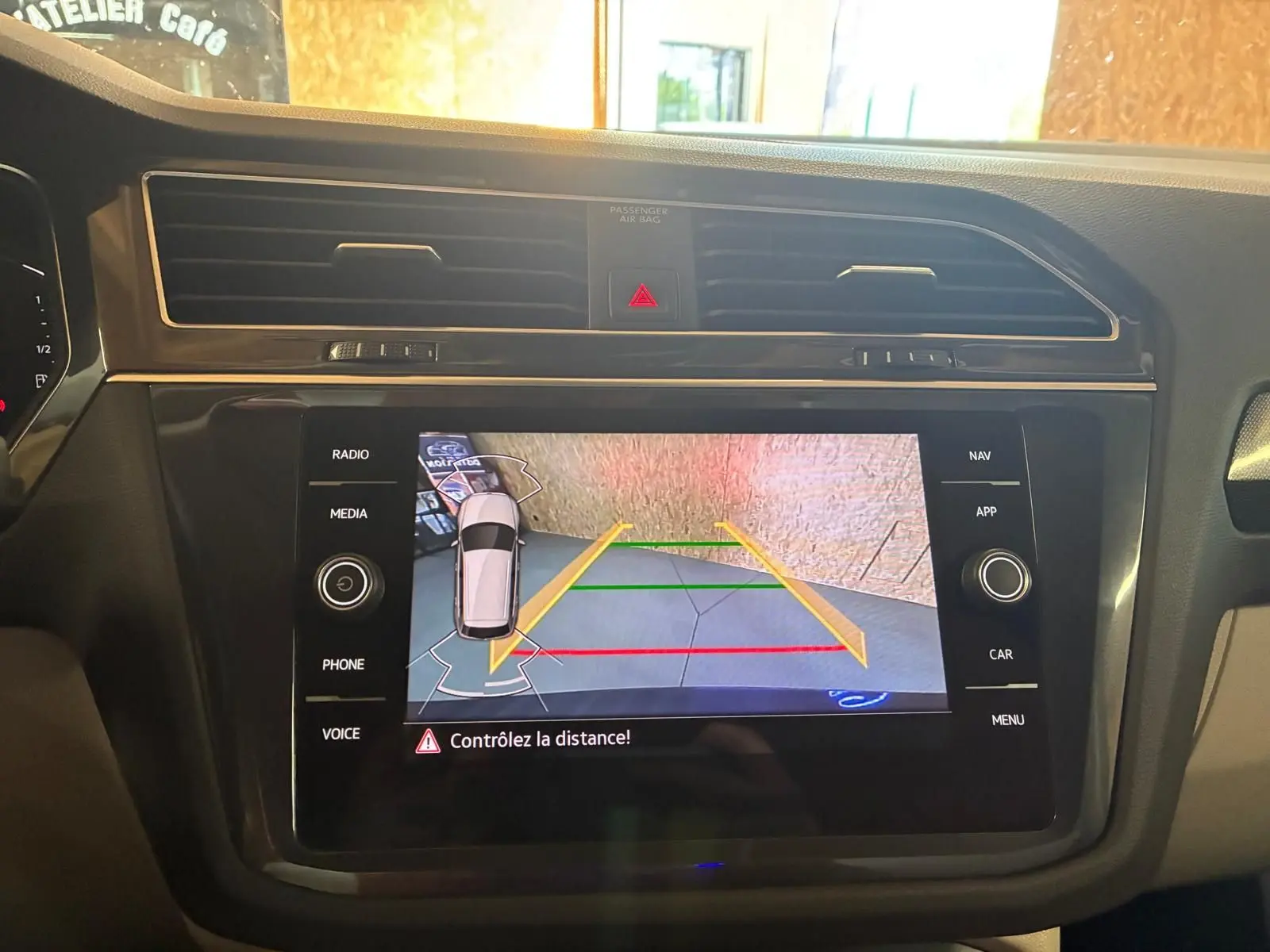 Vue intérieure du tableau de bord du Volkswagen Tiguan 2023, écran tactile affichant la caméra de recul avec guidage coloré.