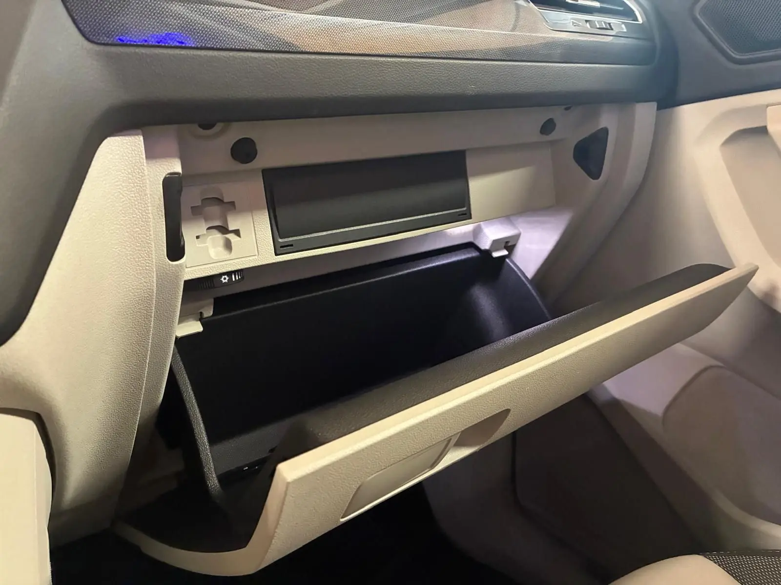 Vue intérieure côté passager du Volkswagen Tiguan 2023, boîte à gants beige ouverte avec tableau de bord noir.