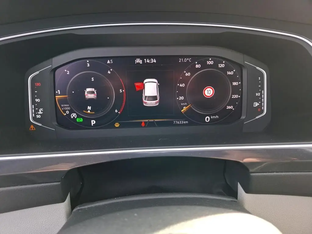 Vue rapprochée du tableau de bord digital du Volkswagen Tiguan 2023 affichant la vitesse, la température et l'alerte porte ouverte.