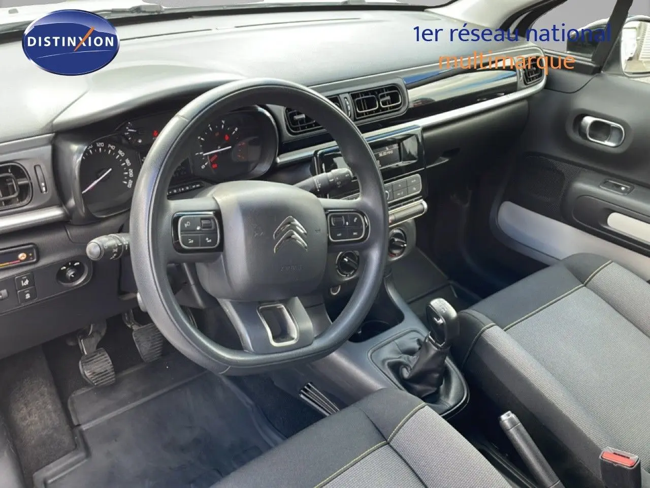 Vue intérieure côté conducteur de la Citroën C3 Société 2019, tableau de bord gris noir avec volant multifonctions.