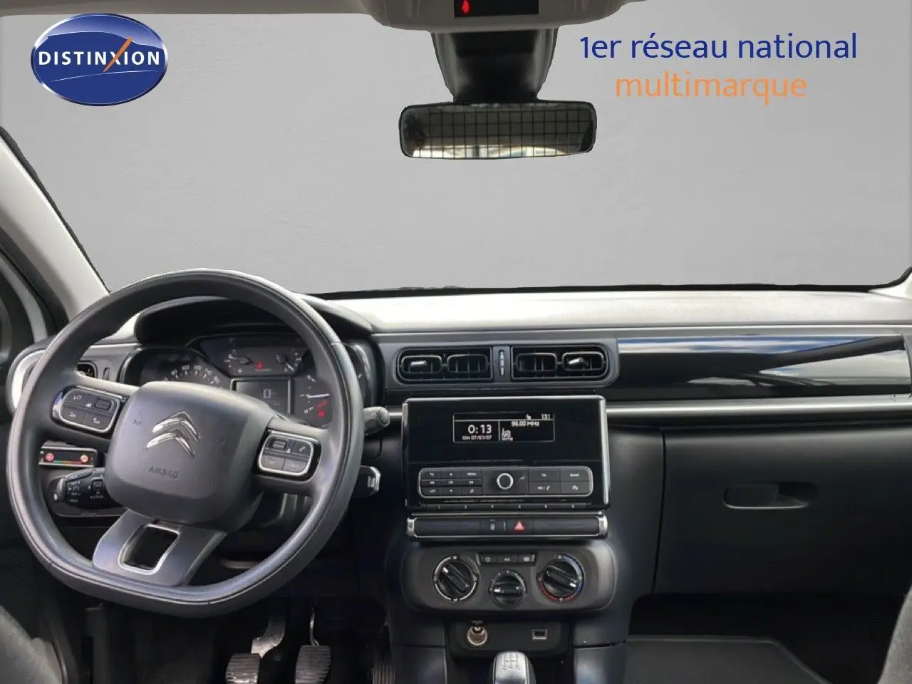 Vue intérieure avant du tableau de bord noir et gris d'une Citroën C3 Société blanche avec volant multifonction et écran central.