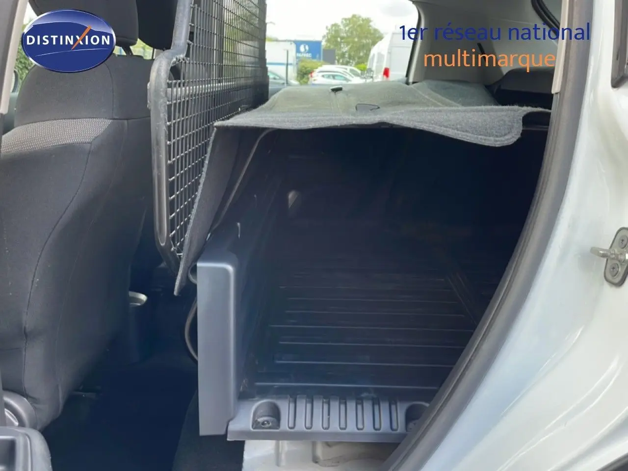 Vue intérieure côté droit du coffre utilitaire blanc banquise d'une Citroën C3 Société 2019 avec cloison métallique et tapis de protection.