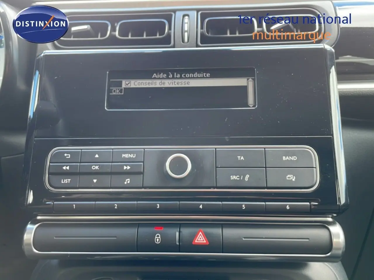 Vue rapprochée du tableau de bord noir de la Citroën C3 Société blanc banquise, avec écran d’aide à la conduite et commandes radio.