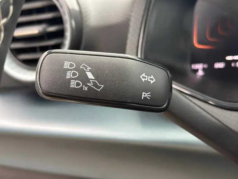Gros plan sur la commande de clignotants noire à gauche du volant dans le tableau de bord du SEAT Arona blanc 2025.