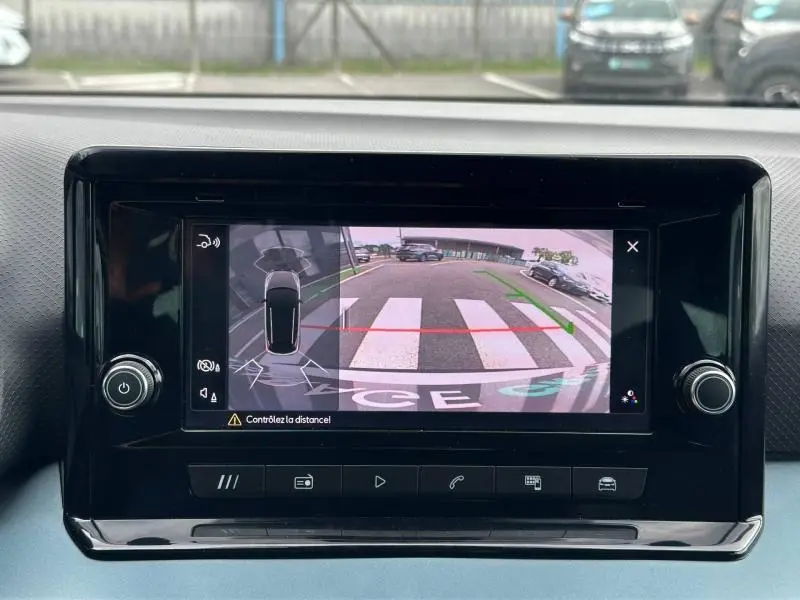 Écran tactile intérieur montrant la caméra de recul avec vue arrière et lignes de guidage du SEAT Arona blanc.