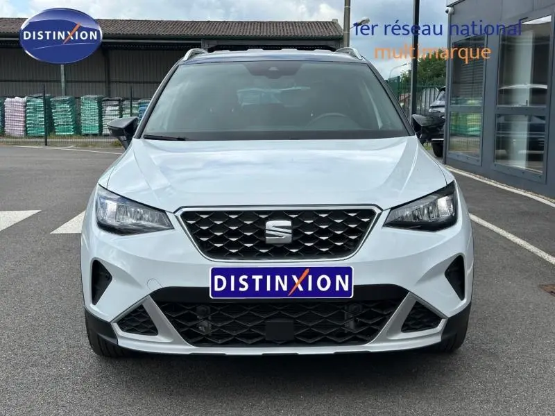 Vue avant d'un SEAT Arona blanc Nevada avec toit noir, mettant en valeur la calandre et les phares LED.