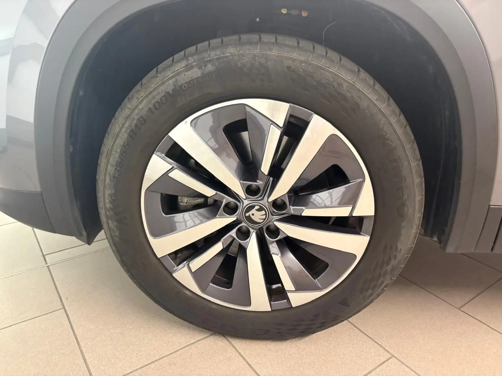 Gros plan sur la roue avant gauche d’un Skoda Kodiaq gris graphite, mettant en valeur la jante alliage bicolore.
