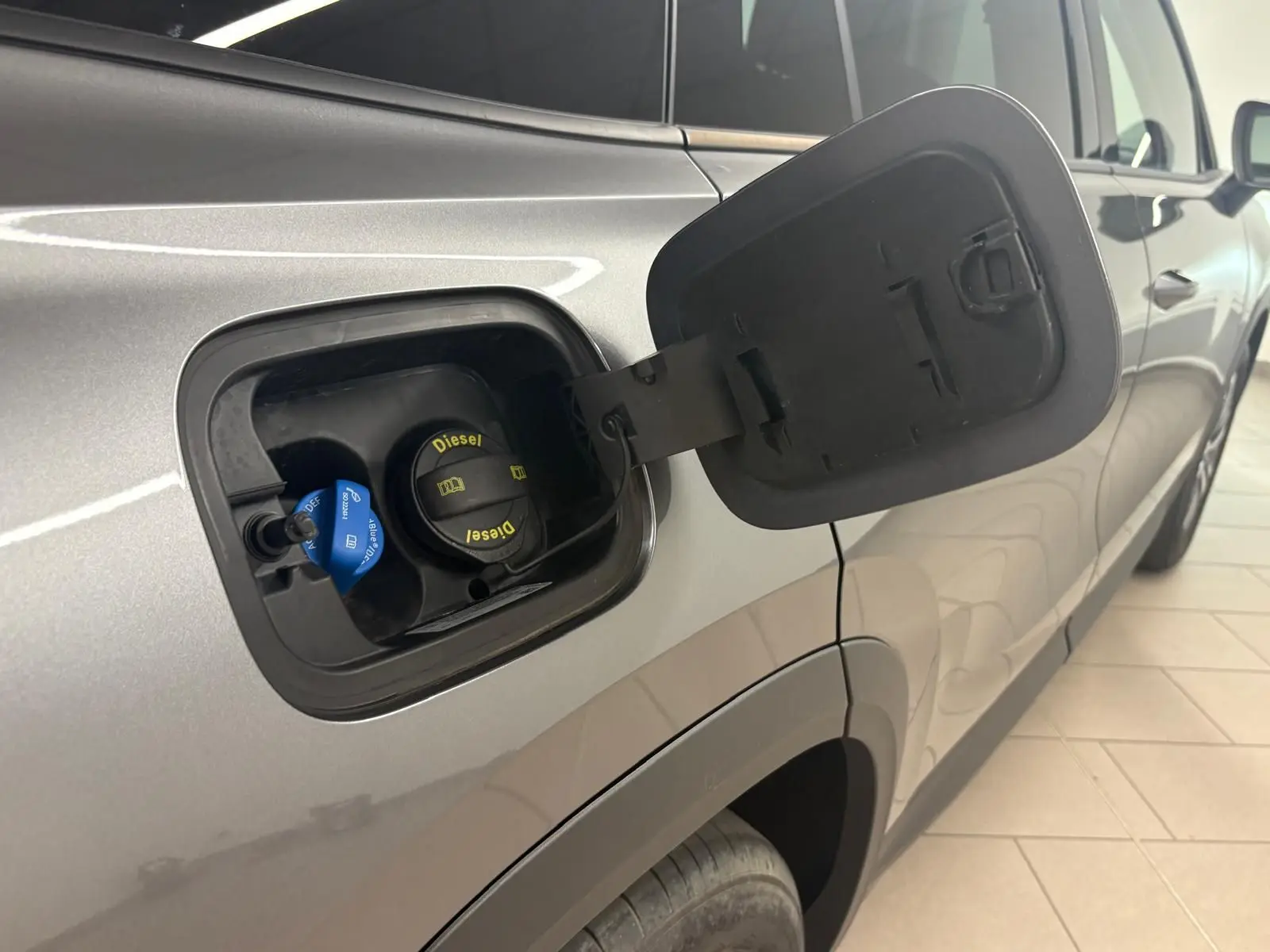 Vue de côté droit du Skoda Kodiaq gris graphite 2025, trappe à carburant ouverte montrant le bouchon diesel et AdBlue.