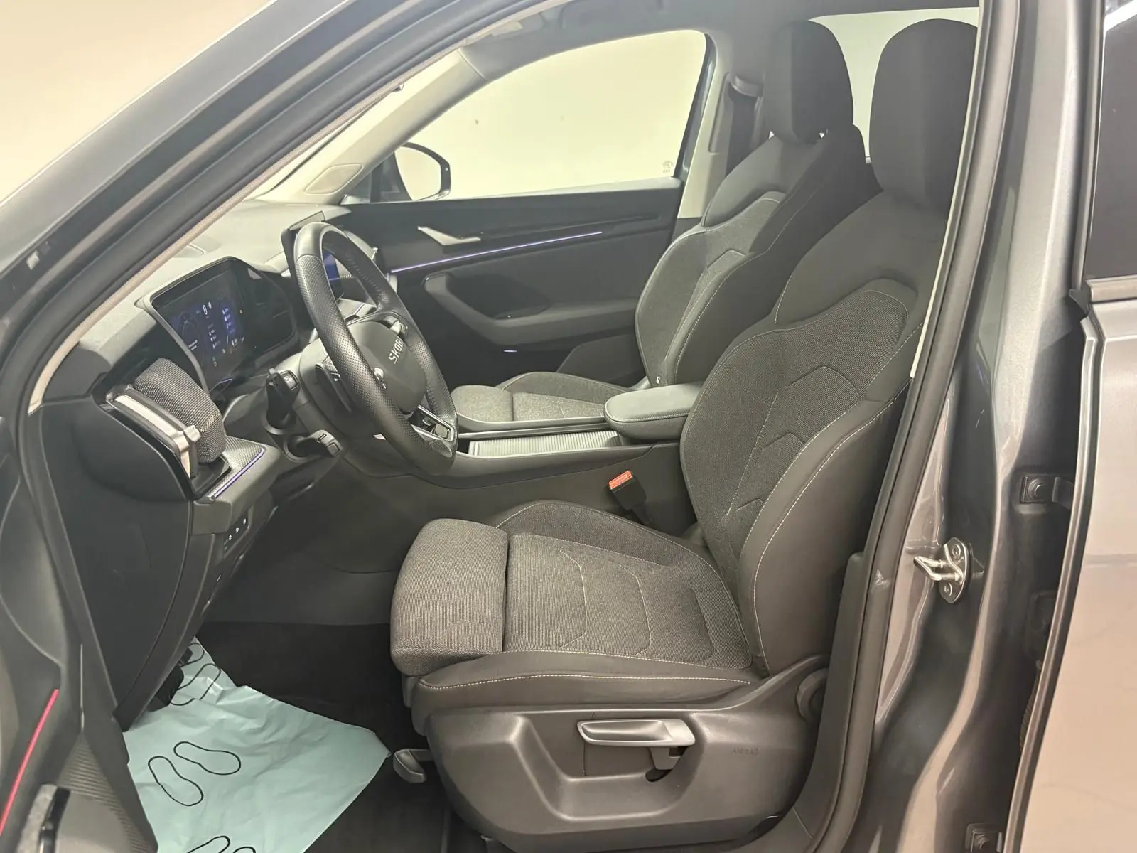 Vue intérieure côté conducteur du Skoda Kodiaq gris graphite 2025, montrant les sièges avant et le tableau de bord moderne.