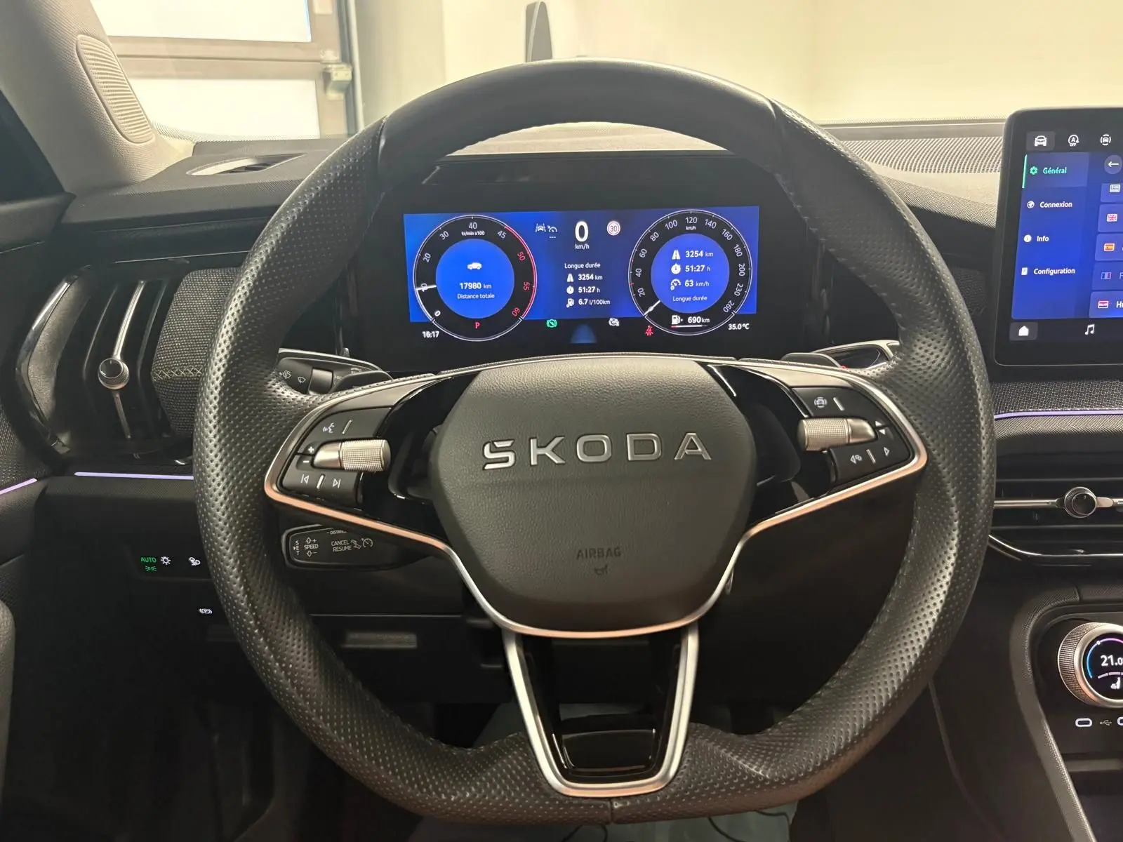 Vue intérieure centrée sur le volant perforé noir du Skoda Kodiaq 2025 avec tableau de bord numérique et écran tactile.